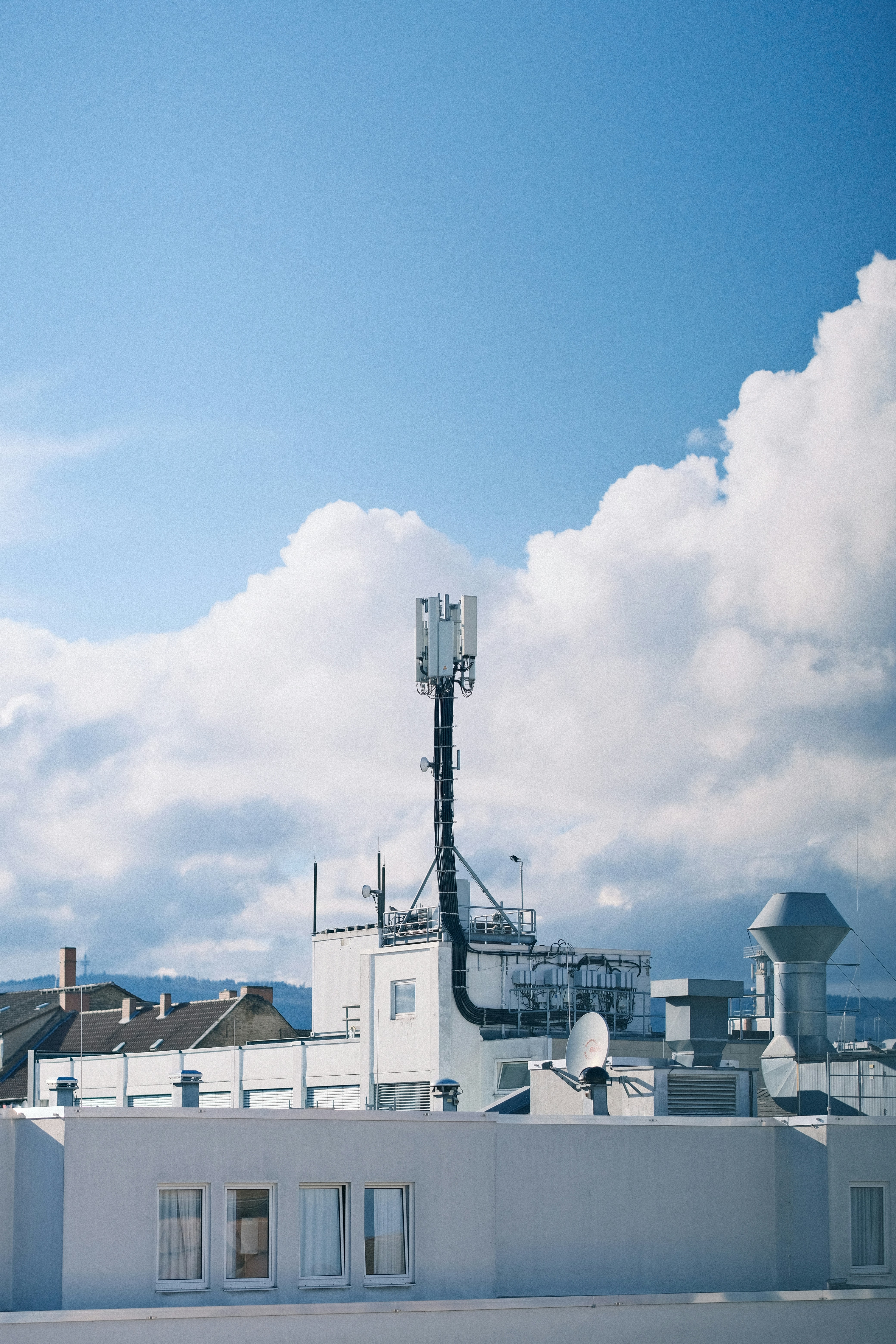 Cell antenna mounted on a building rooftop, blending into the urban landscape