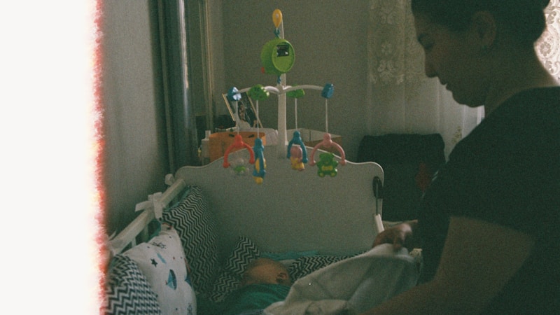 A mother tucking her baby into a crib — the nursery environment matters more than most parents realize